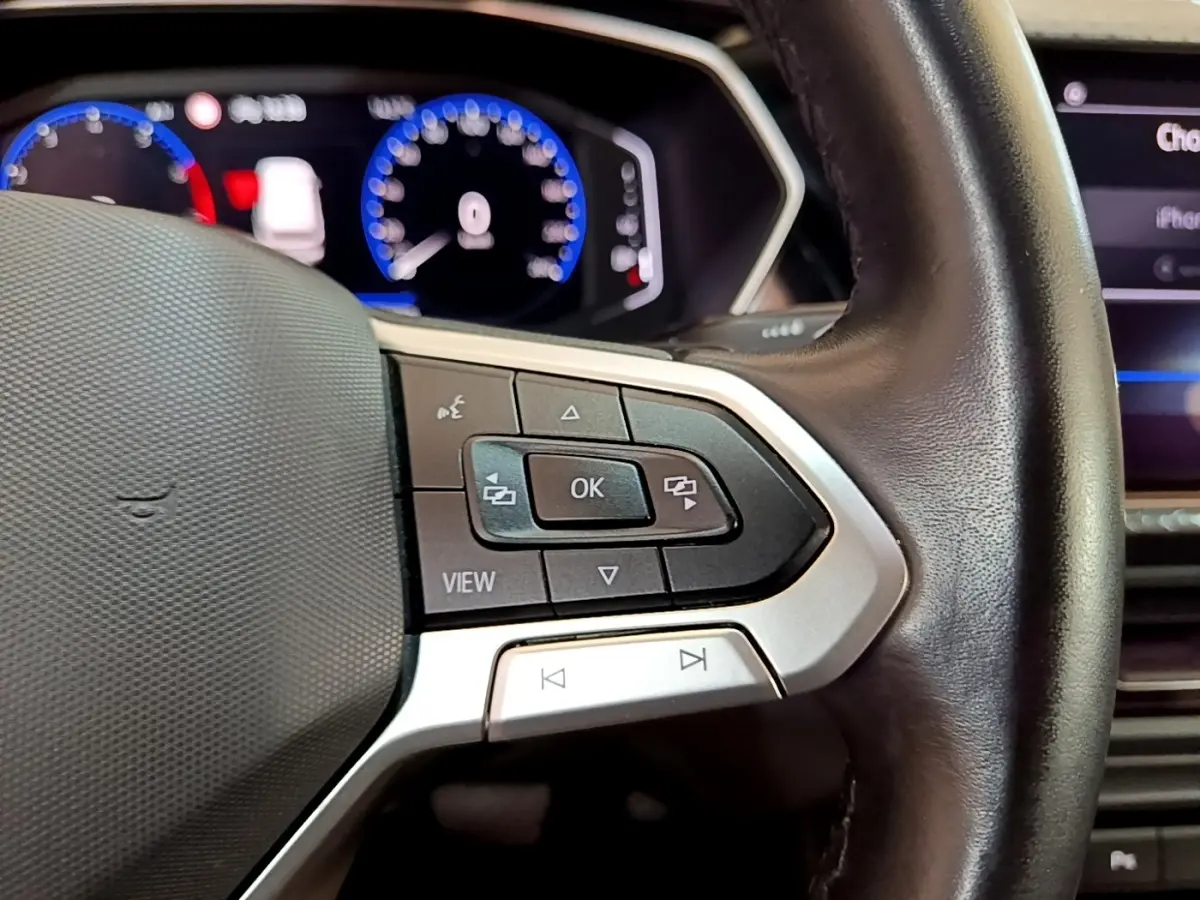 Gros plan sur le volant cuir noir du Volkswagen T-Cross 2022, avec commandes multifonctions et tableau de bord numérique.