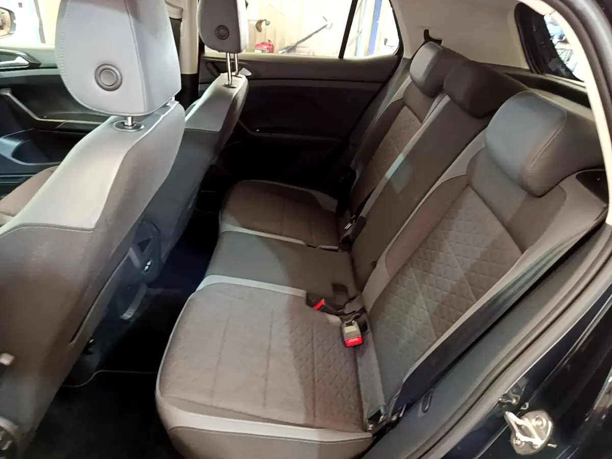 Vue intérieure côté droit sur la banquette arrière grise du Volkswagen T-Cross noir, avec portes ouvertes.
