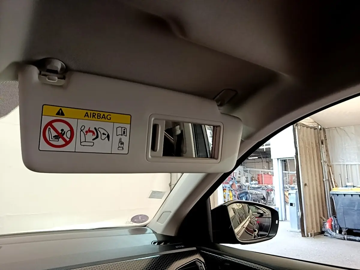 Vue intérieure du pare-soleil côté conducteur avec miroir et avertissement airbag dans un Volkswagen T-Cross noir 2022.