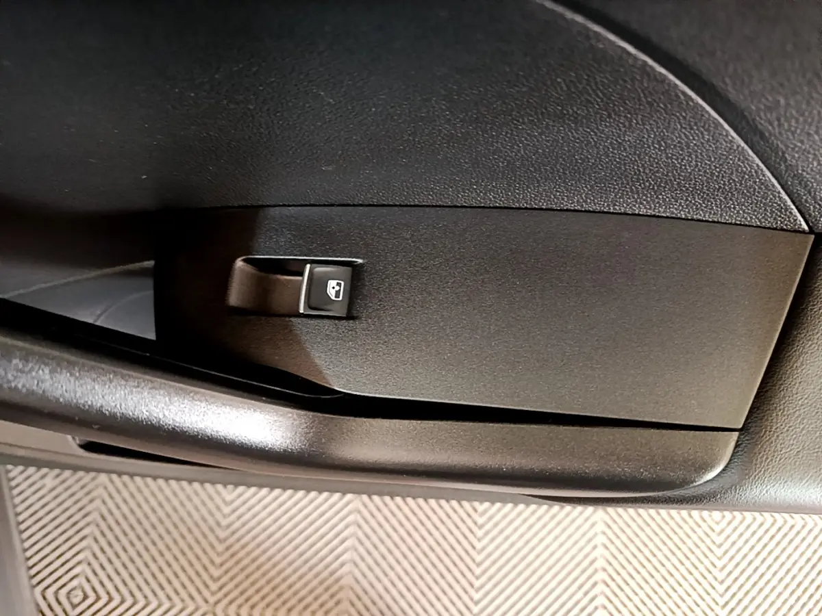 Gros plan sur la commande de lève-vitre arrière noire dans l'habitacle du Volkswagen T-Cross noir.
