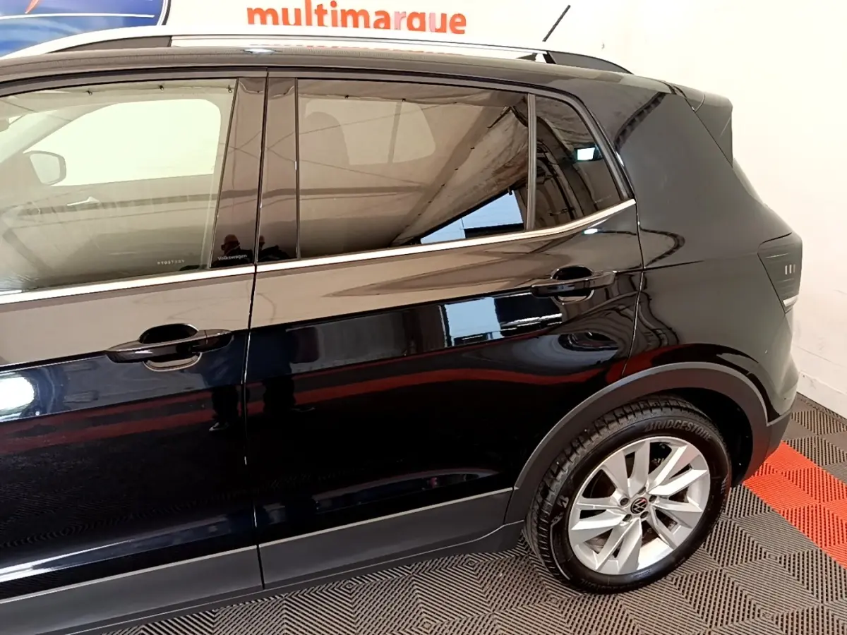 Vue latérale côté droit du Volkswagen T-Cross noir, mettant en valeur les jantes alliage et les vitres teintées.