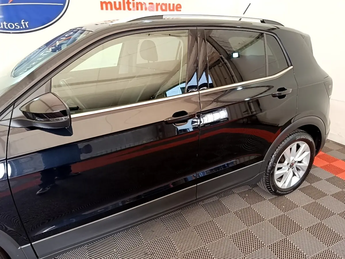 Vue de profil côté gauche d'un Volkswagen T-Cross noir brillant avec jantes alliage et rétroviseur électrique.