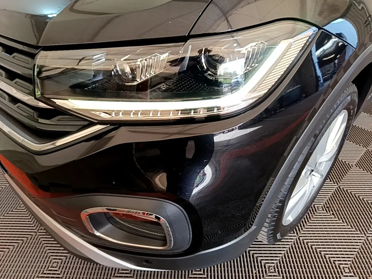 Gros plan sur l'avant droit noir du Volkswagen T-Cross 2022, mettant en valeur le phare LED et la calandre chromée.