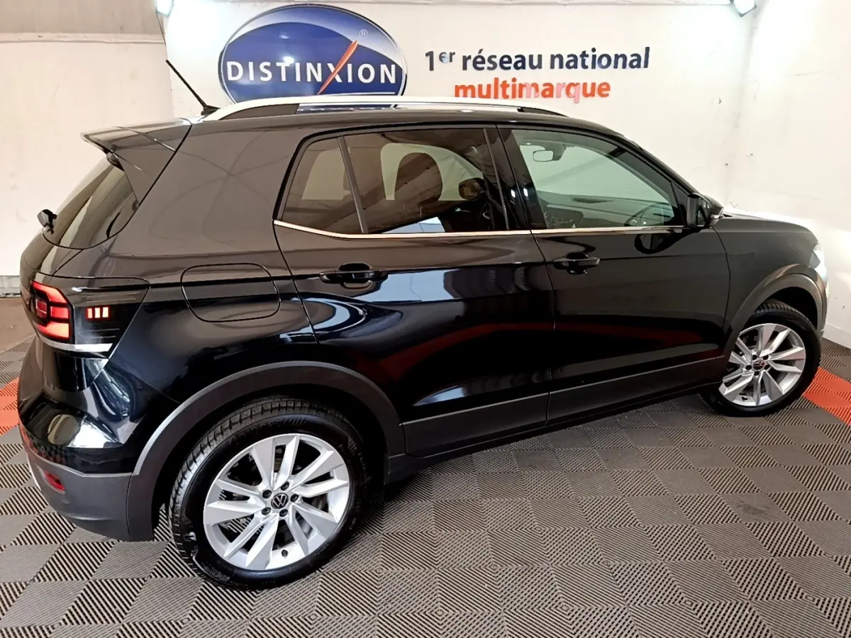 Volkswagen T-Cross noir vue de profil côté droit, avec jantes alliage et vitres teintées en intérieur showroom.