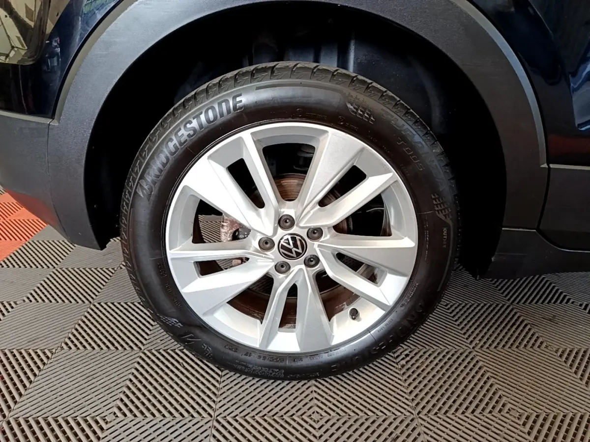Gros plan sur la roue avant droite d’un Volkswagen T-Cross noir, jante alliage argentée et pneu Bridgestone.