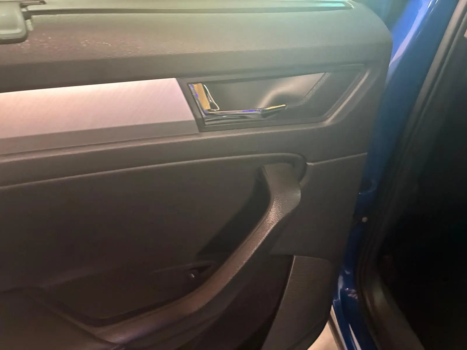 Vue intérieure du panneau de porte côté gauche d'un Skoda Kodiaq bleu 2023 avec poignée noire et insert décoratif gris.