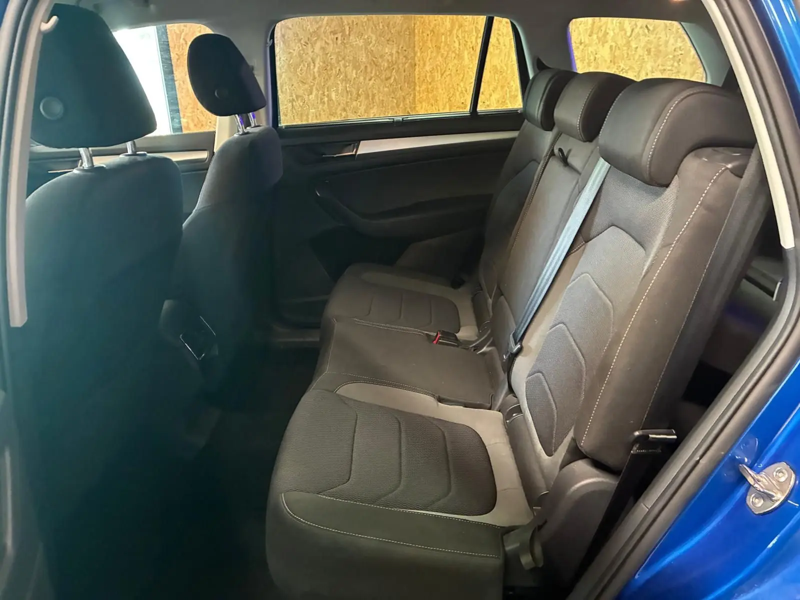 Vue intérieure côté droit des sièges arrière en tissu noir du Skoda Kodiaq bleu 2023, porte arrière ouverte.
