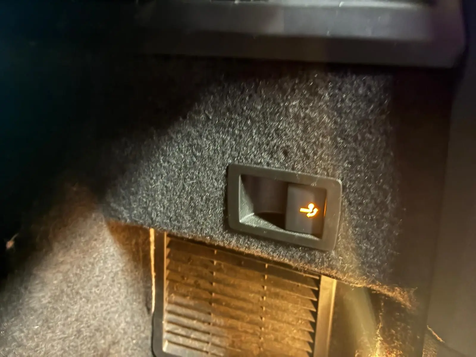 Détail intérieur montrant un bouton de déverrouillage de siège arrière illuminé sur un Skoda Kodiaq bleu 2023.