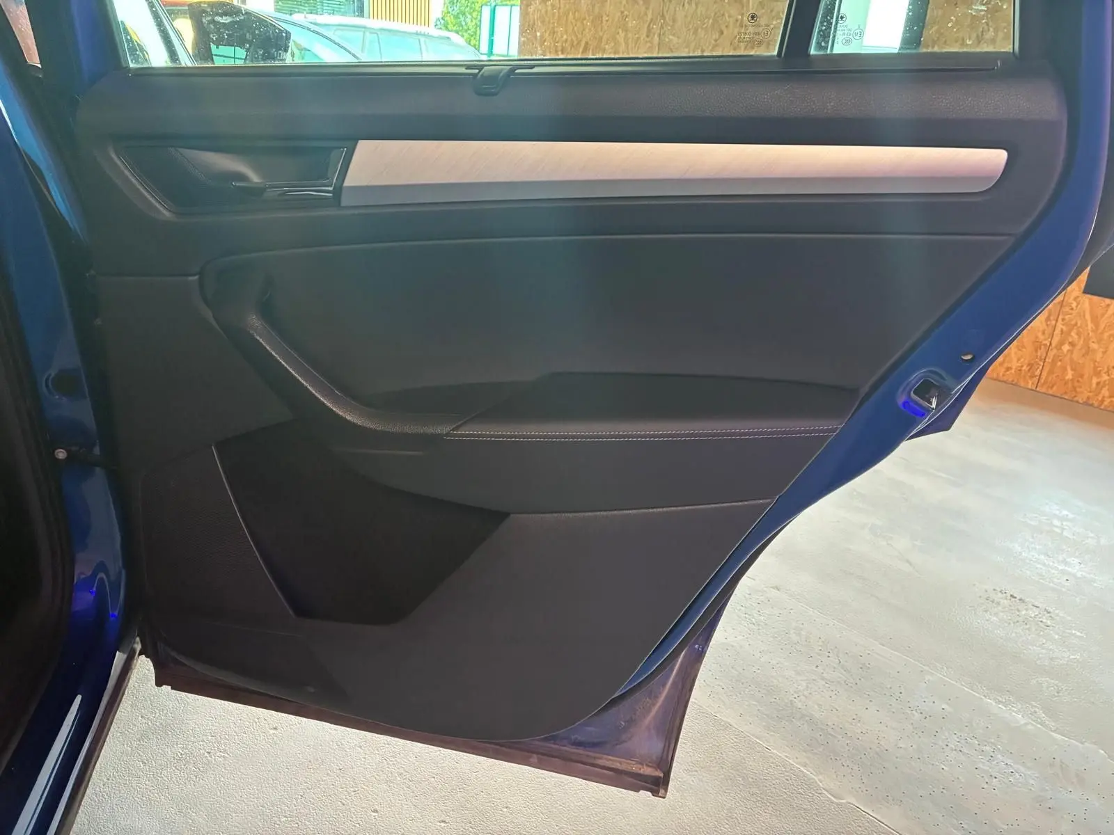 Vue intérieure de la porte arrière gauche d’un Skoda Kodiaq bleu 2023, avec garniture noire et insert décoratif clair.