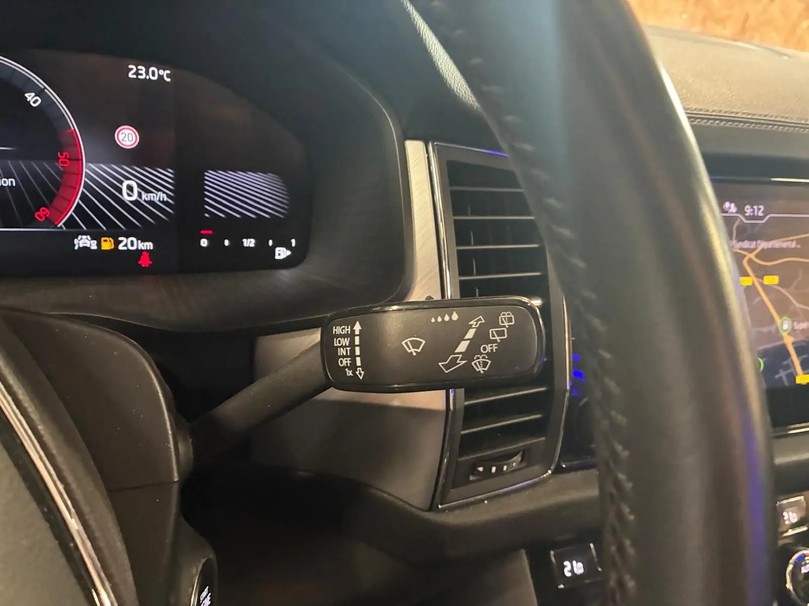 Gros plan intérieur sur le commodo d’essuie-glace côté gauche du Skoda Kodiaq bleu 2023, avec tableau de bord numérique et écran GPS visibles.