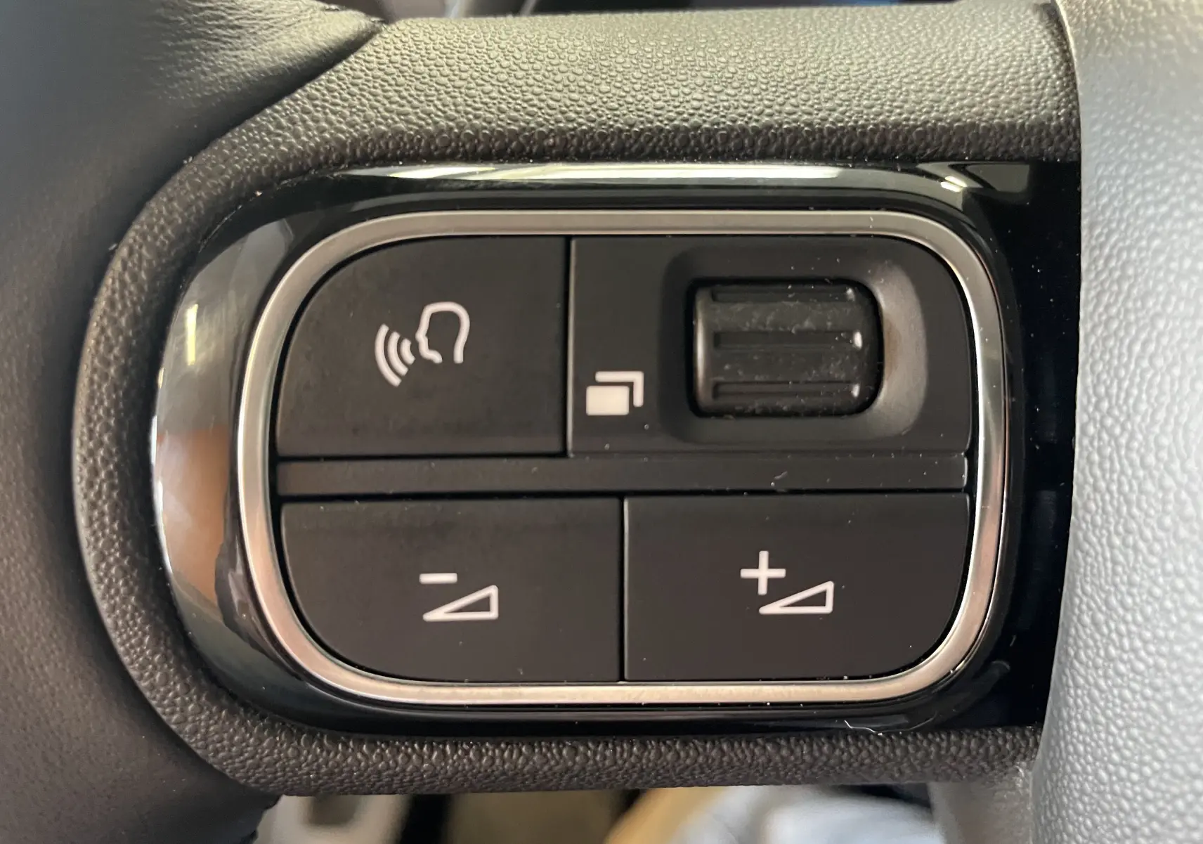 Gros plan sur les commandes au volant du Citroën C5 Aircross hybride gris platinium, avec boutons de volume et fonction mains libres.