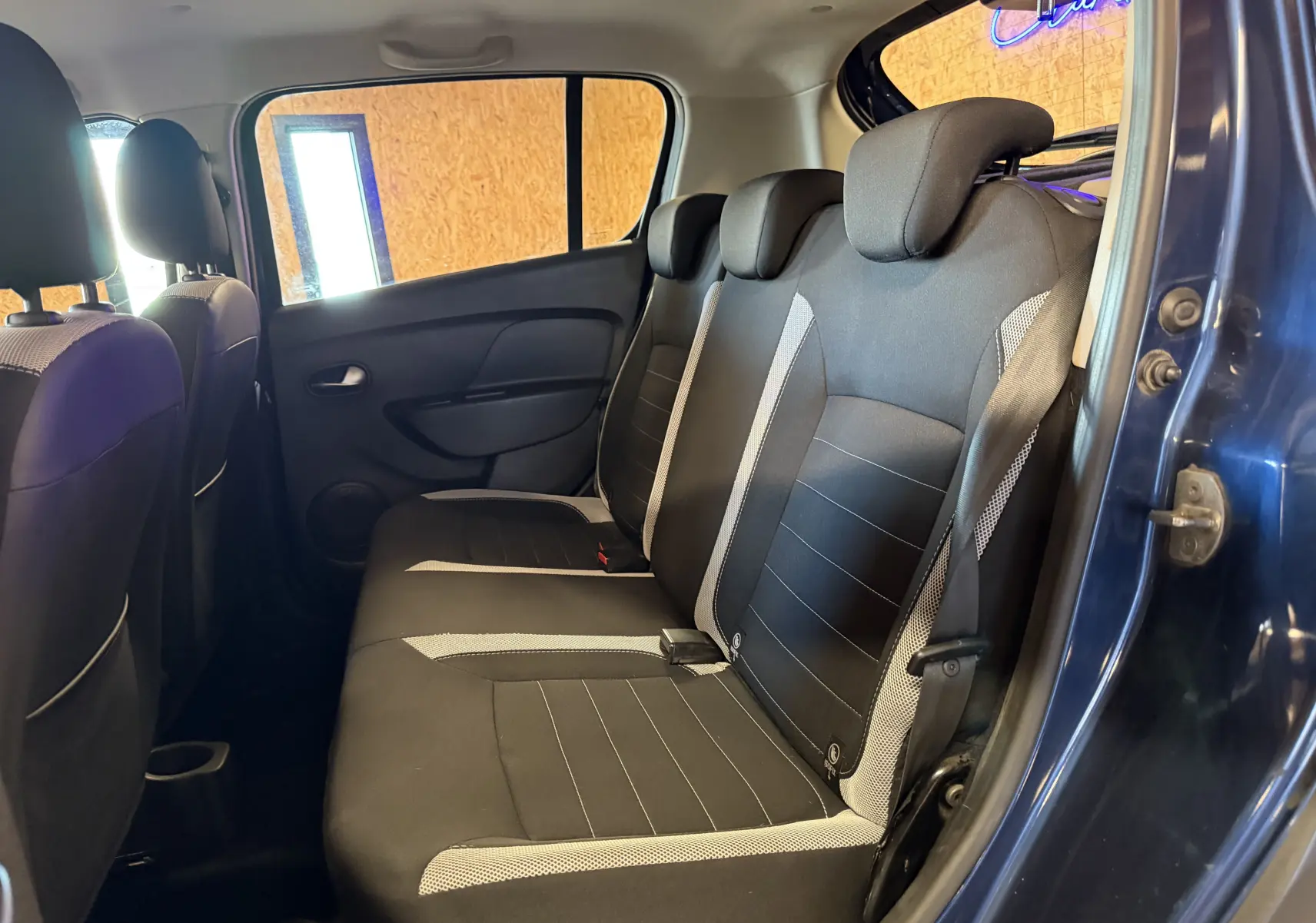 Vue intérieure côté droit des sièges arrière noirs et gris du Dacia Sandero Stepway bleu 2019 avec porte ouverte.