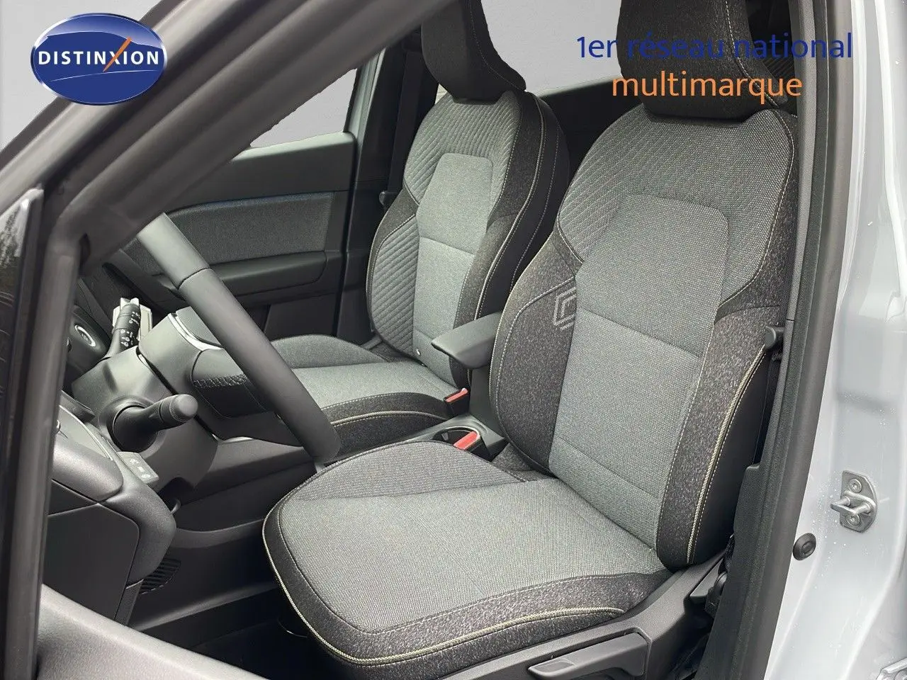 Vue intérieure côté conducteur du Renault Captur E-Tech gris Rafale avec sièges tissu gris et beige, volant et tableau de bord visibles.