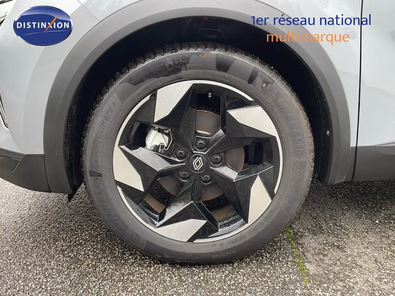 Gros plan sur la roue avant gauche du Renault Captur gris Rafale avec jante noire et argentée au design étoilé.