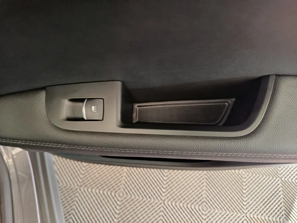 Détail de la commande de lève-vitre sur la porte intérieure côté gauche de l'Alfa Romeo Stelvio gris foncé 2024.