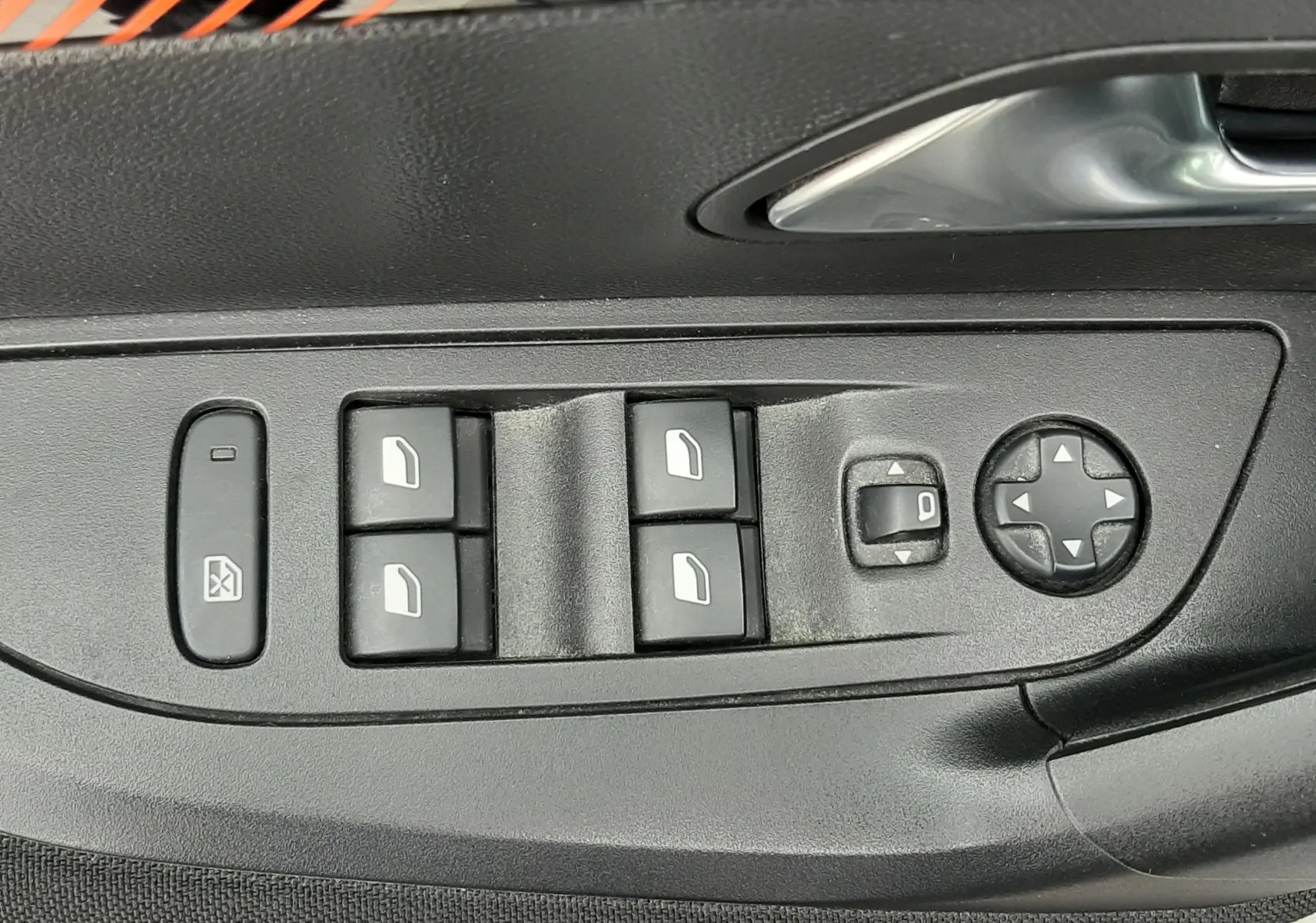Gros plan sur les commandes des vitres et rétroviseurs électriques sur la porte côté conducteur d’un Peugeot 2008 gris Artense.