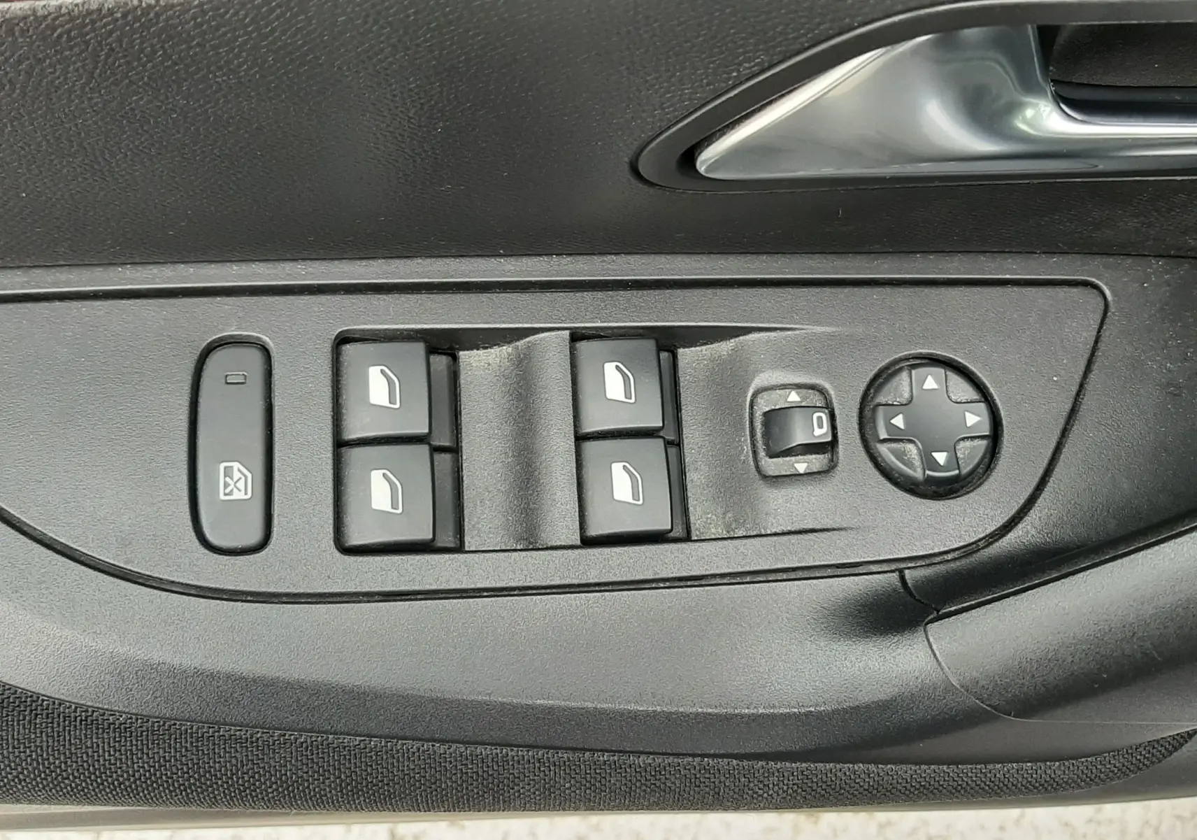 Gros plan sur la commande des vitres et rétroviseurs électriques côté conducteur d'une Peugeot 2008 gris Artense.