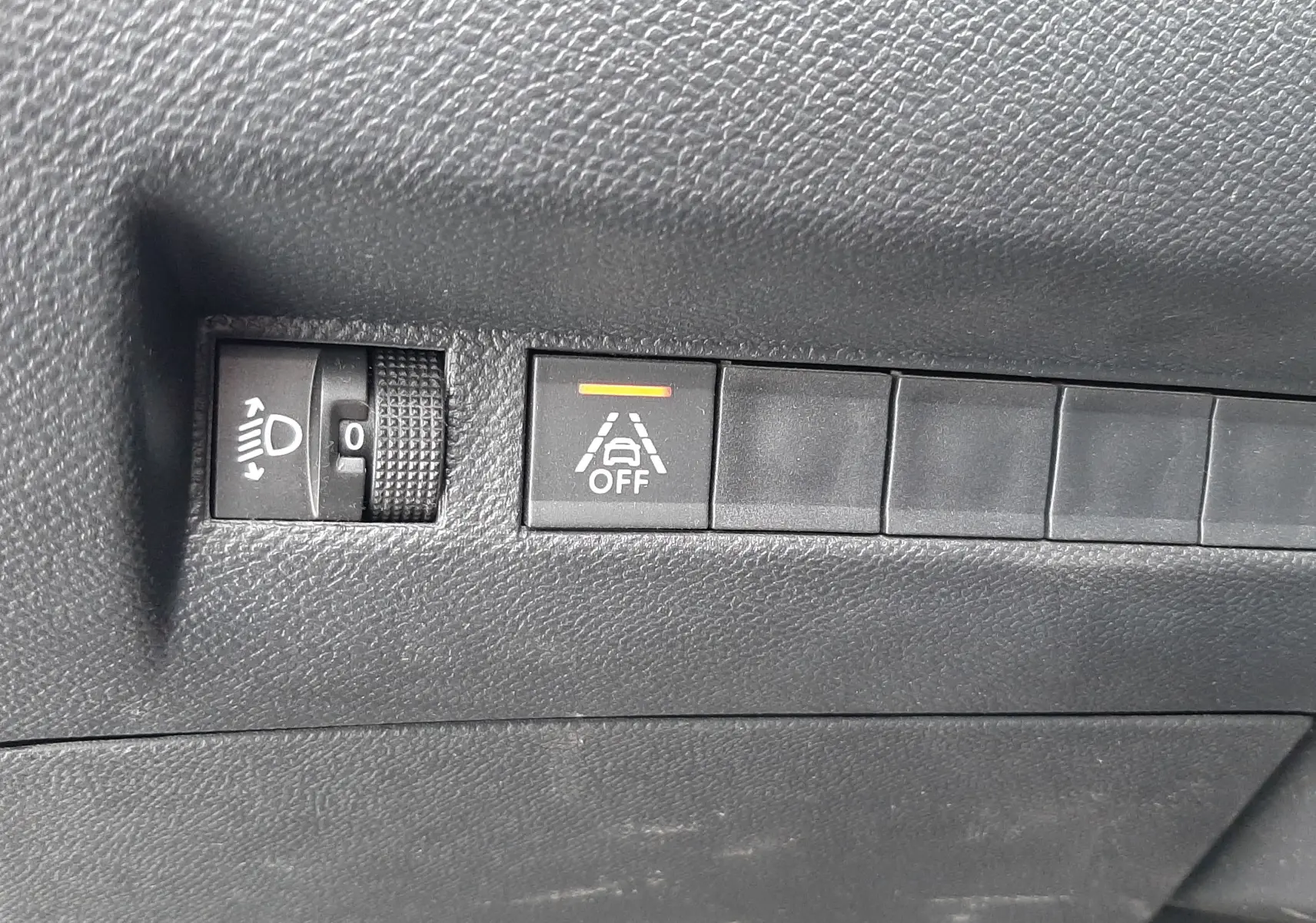 Gros plan sur les commandes de réglage des phares et de désactivation de l'alerte de franchissement de ligne dans un Peugeot 2008 gris Artense.