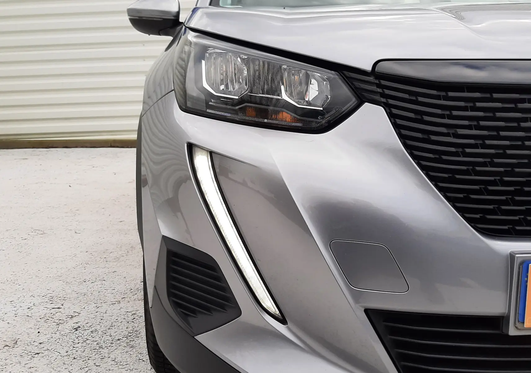 Vue rapprochée 3/4 avant gauche du Peugeot 2008 gris Artense avec ses phares et feux diurnes LED distinctifs.