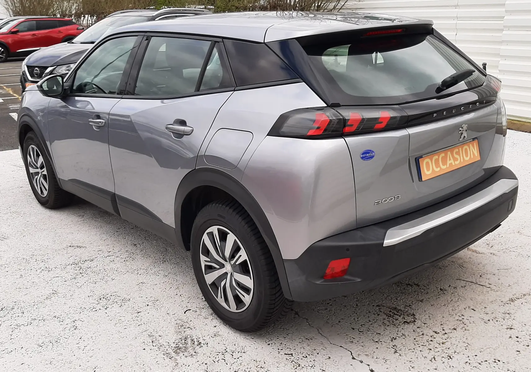 Peugeot 2008 gris Artense vue 3/4 arrière droit, feux arrière à griffes rouges et toit noir contrasté.