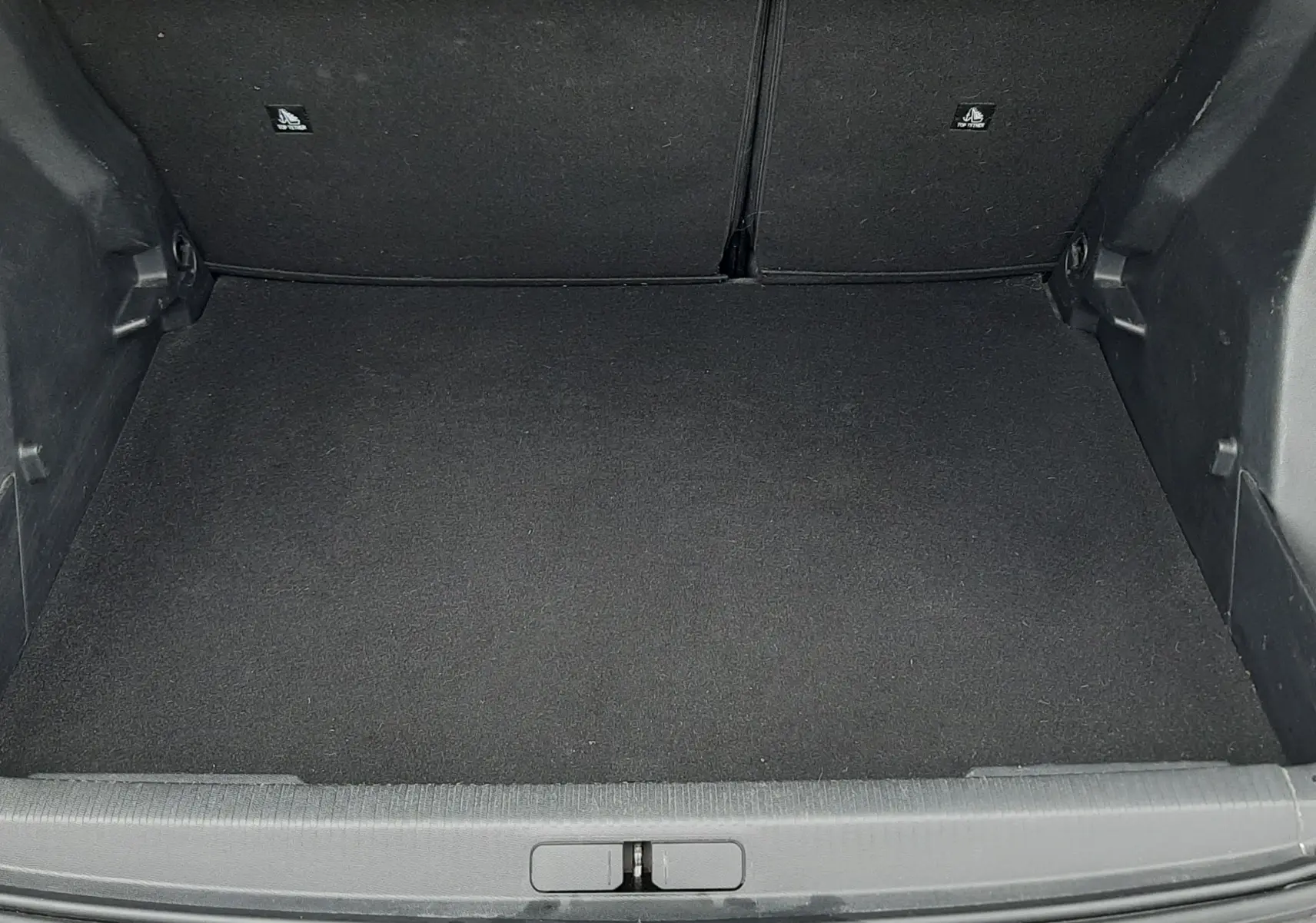 Coffre ouvert vu de face d'un Peugeot 2008 gris Artense, montrant un espace de chargement propre et vide.