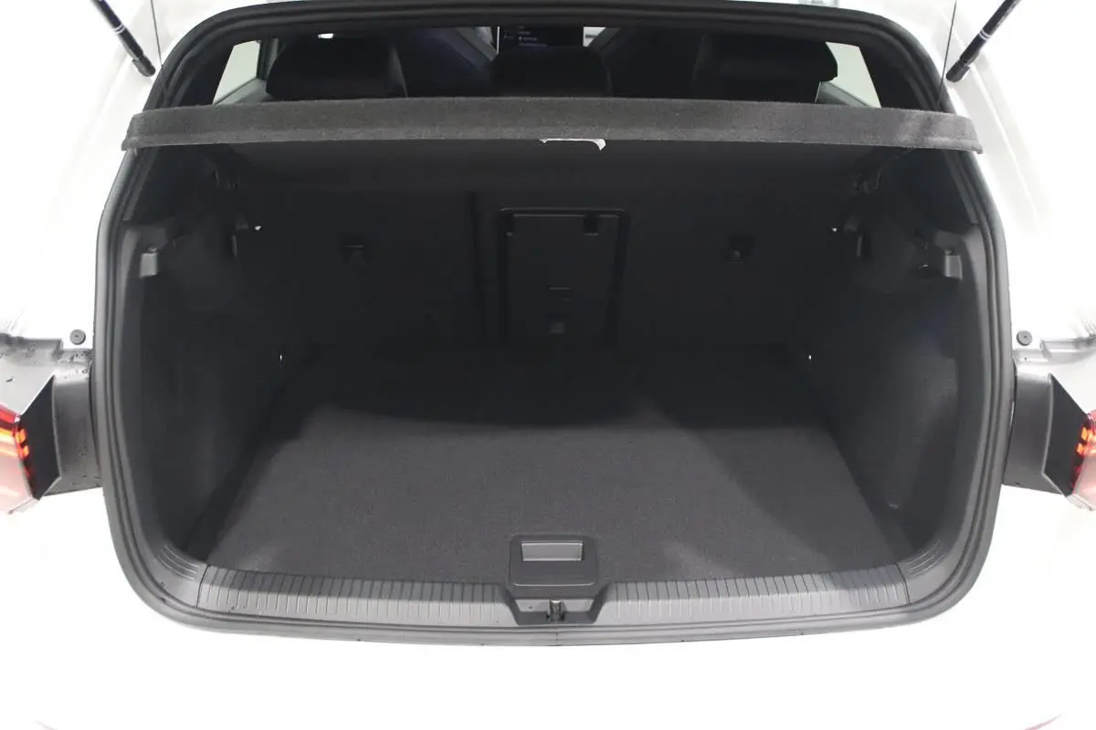 Coffre ouvert vu de l'arrière d'une Volkswagen Golf blanche 2025 avec intérieur noir et hayon relevé.