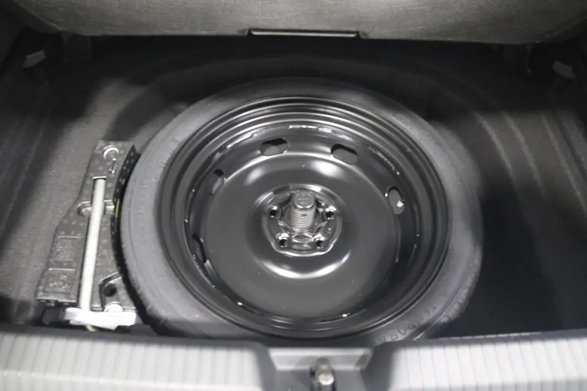Gros plan sur la roue de secours noire dans le coffre d'une Volkswagen Golf blanche 2025.
