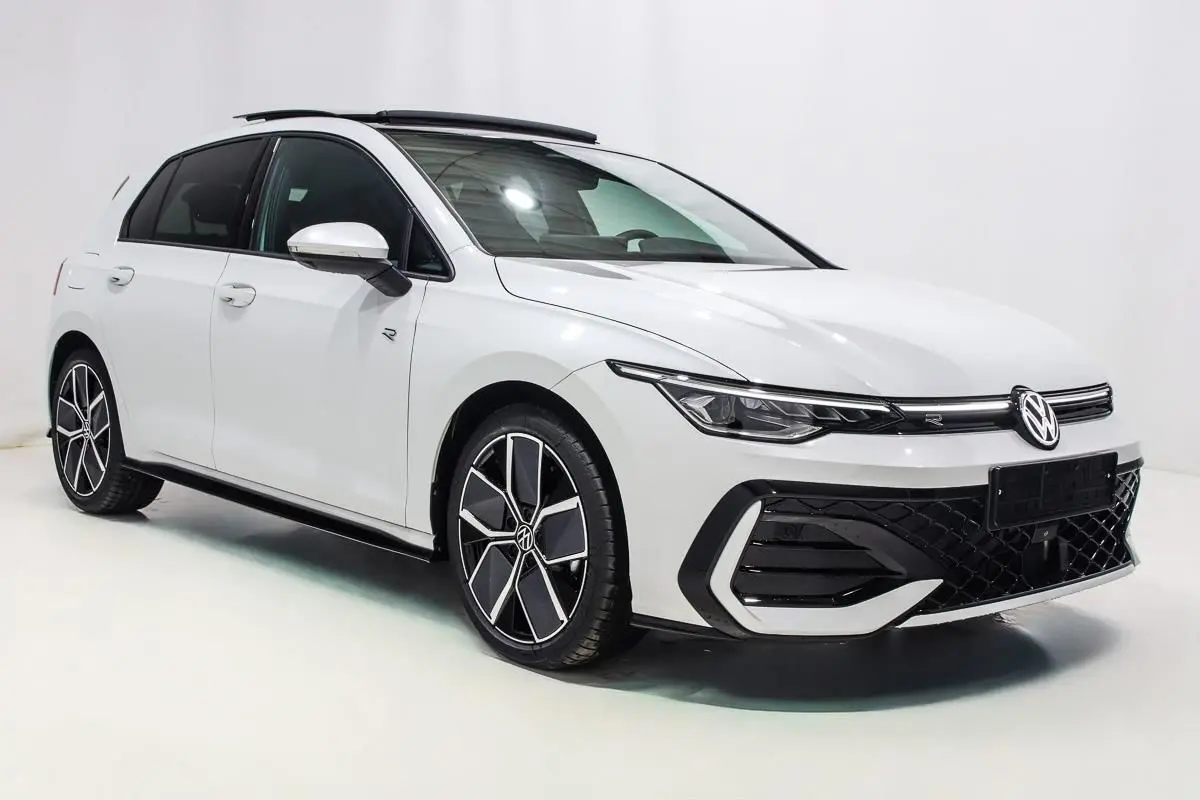 Vue 3/4 avant droite d'une Volkswagen Golf blanche 2025 avec jantes alliage et toit panoramique noir.