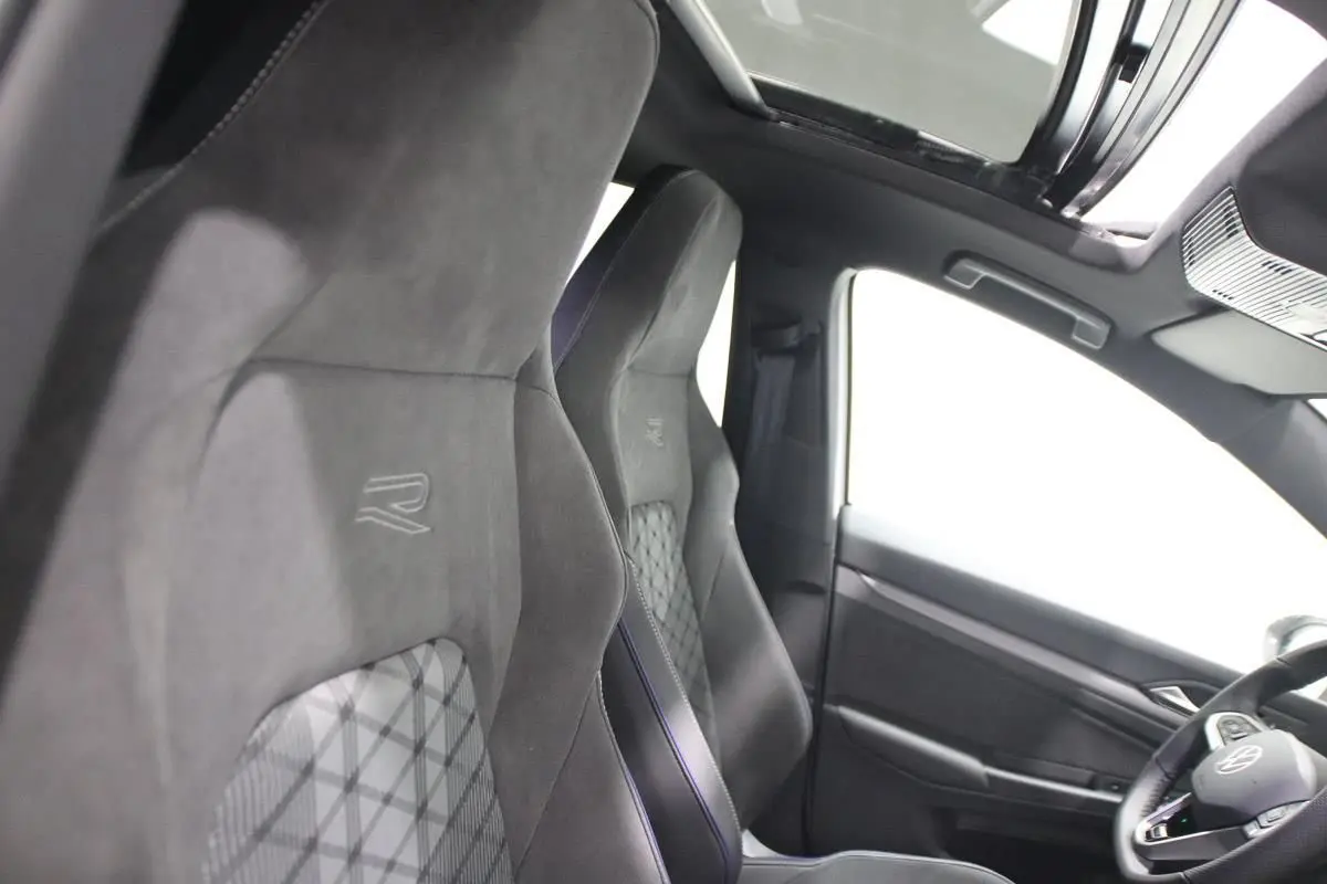 Vue intérieure côté gauche montrant les sièges sport noirs avec logo R et le toit panoramique ouvert.