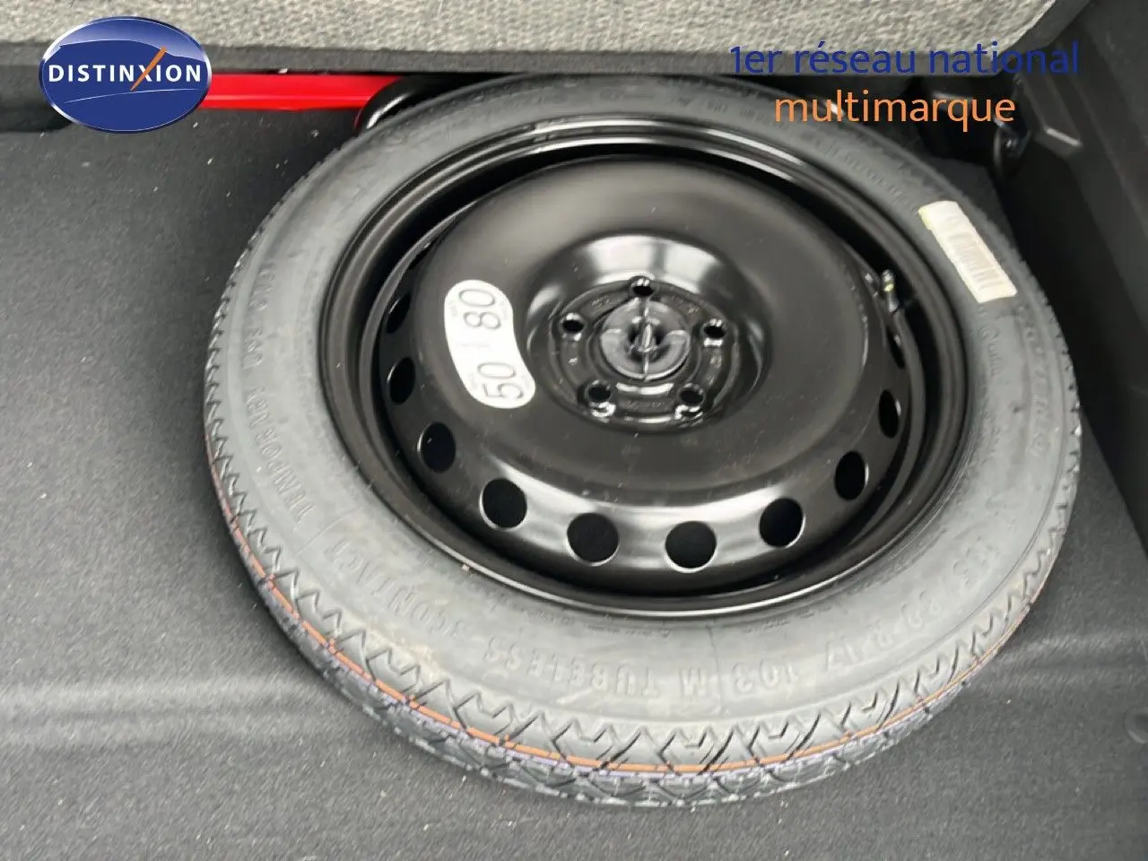 Roue de secours noire en gros plan dans le coffre d’un Renault Symbioz gris Cassiopée Métal.