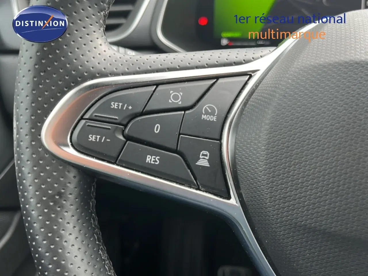 Gros plan sur les commandes de régulateur au volant en cuir perforé d'une Renault Symbioz gris cassiopée metal.