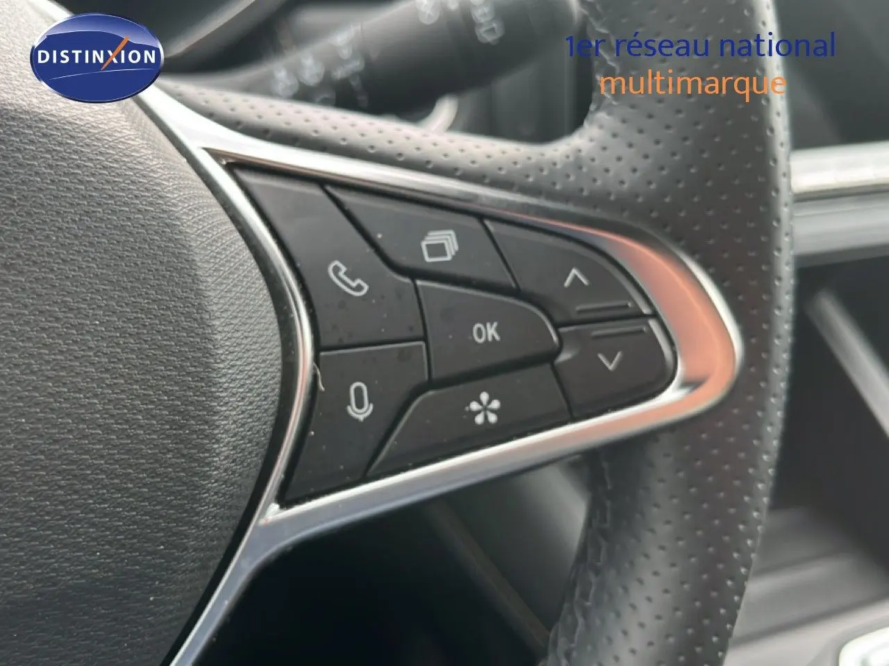 Gros plan sur les commandes multifonctions à gauche du volant perforé du Renault Symbioz gris Cassiopée métal.