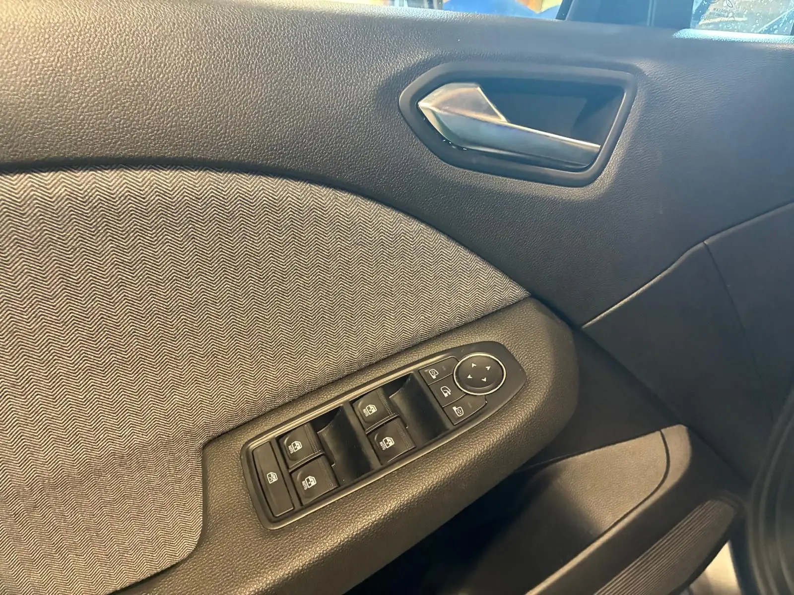 Détail de la porte intérieure côté conducteur de la Renault Clio 2025 gris schiste, avec commandes des vitres et poignée argentée.