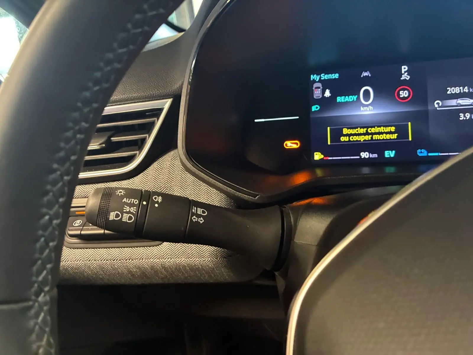 Détail du combiné d'instruments et commodo gauche dans l'habitacle gris noir de la Renault Clio hybride 2025.