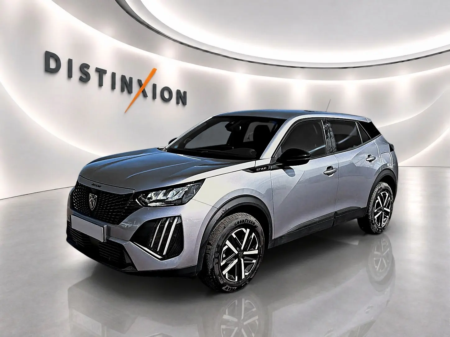 Peugeot 2008 gris en 3/4 avant droit, avec jantes noires et détails noirs sur la calandre et les rétroviseurs.