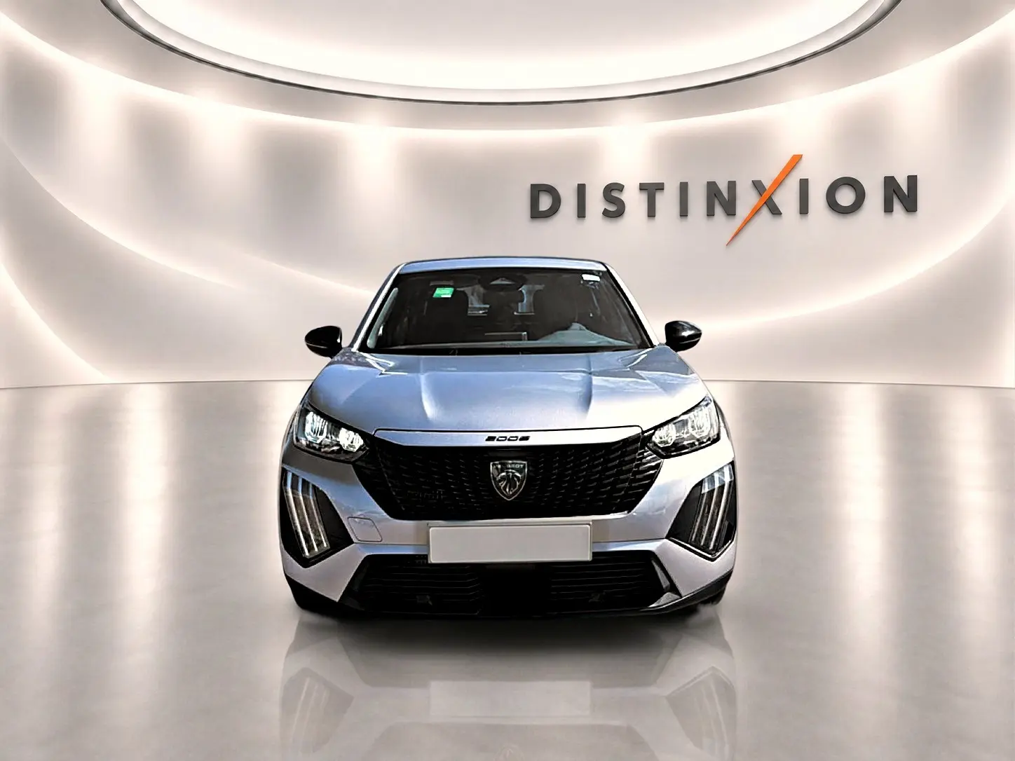 Vue frontale d'un Peugeot 2008 gris 2025 avec calandre noire et feux LED distinctifs dans un showroom lumineux.