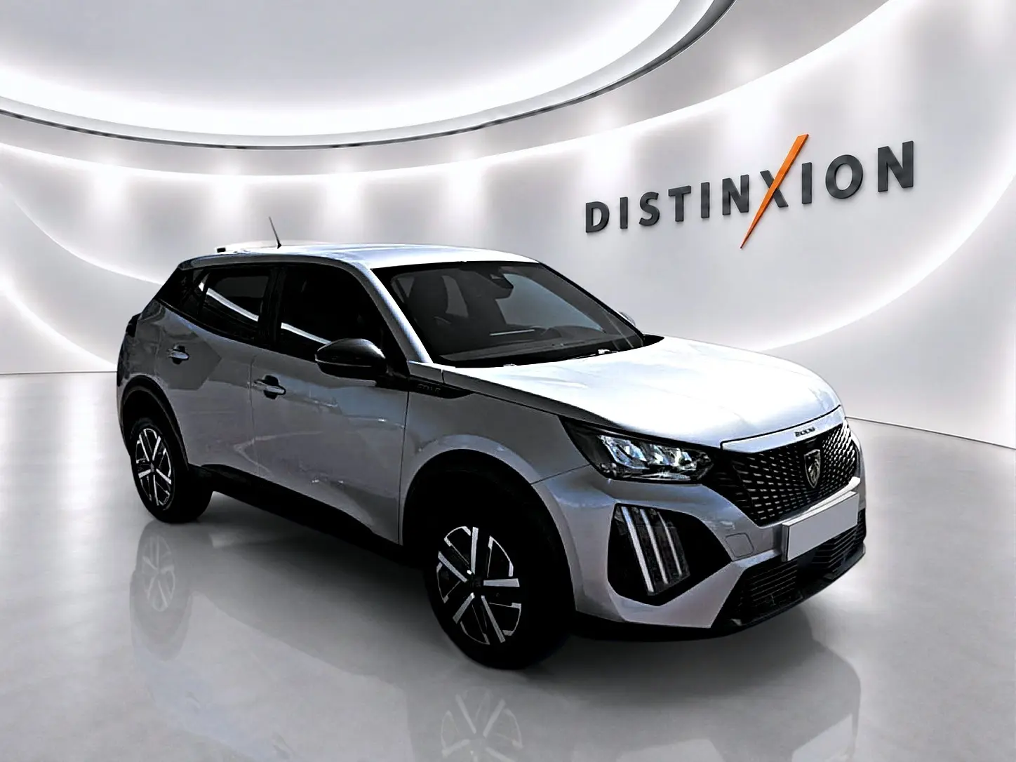 Peugeot 2008 gris en 3/4 avant droit dans un showroom lumineux avec calandre noire distinctive et jantes stylisées.