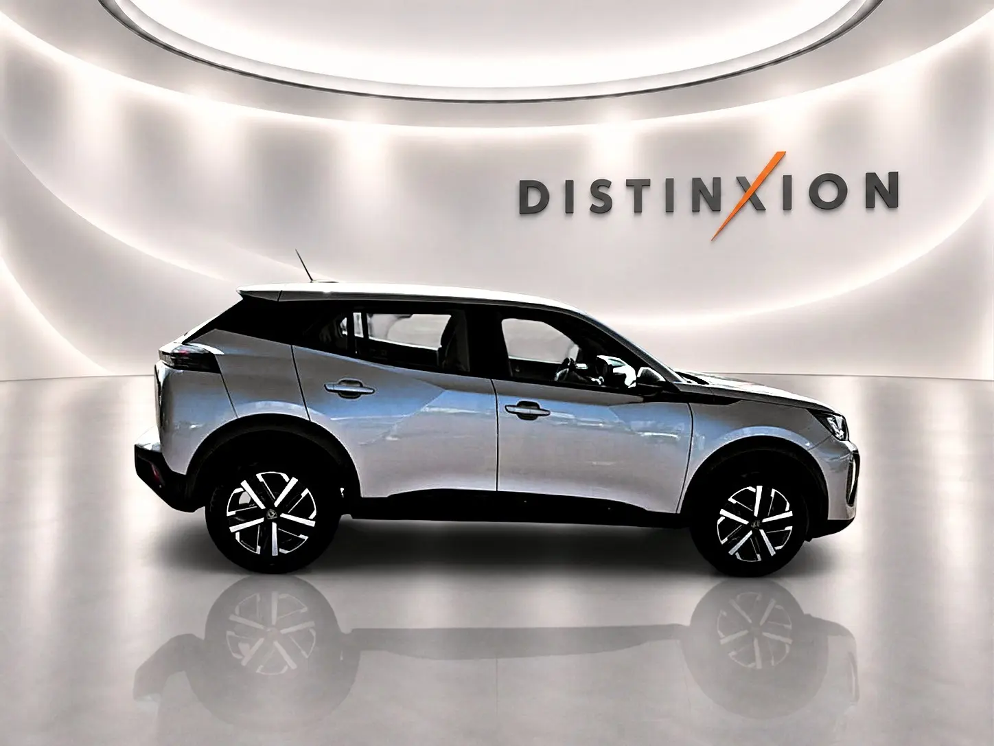 Peugeot 2008 gris en profil droit dans un showroom lumineux avec jantes noires et toit noir contrastant.