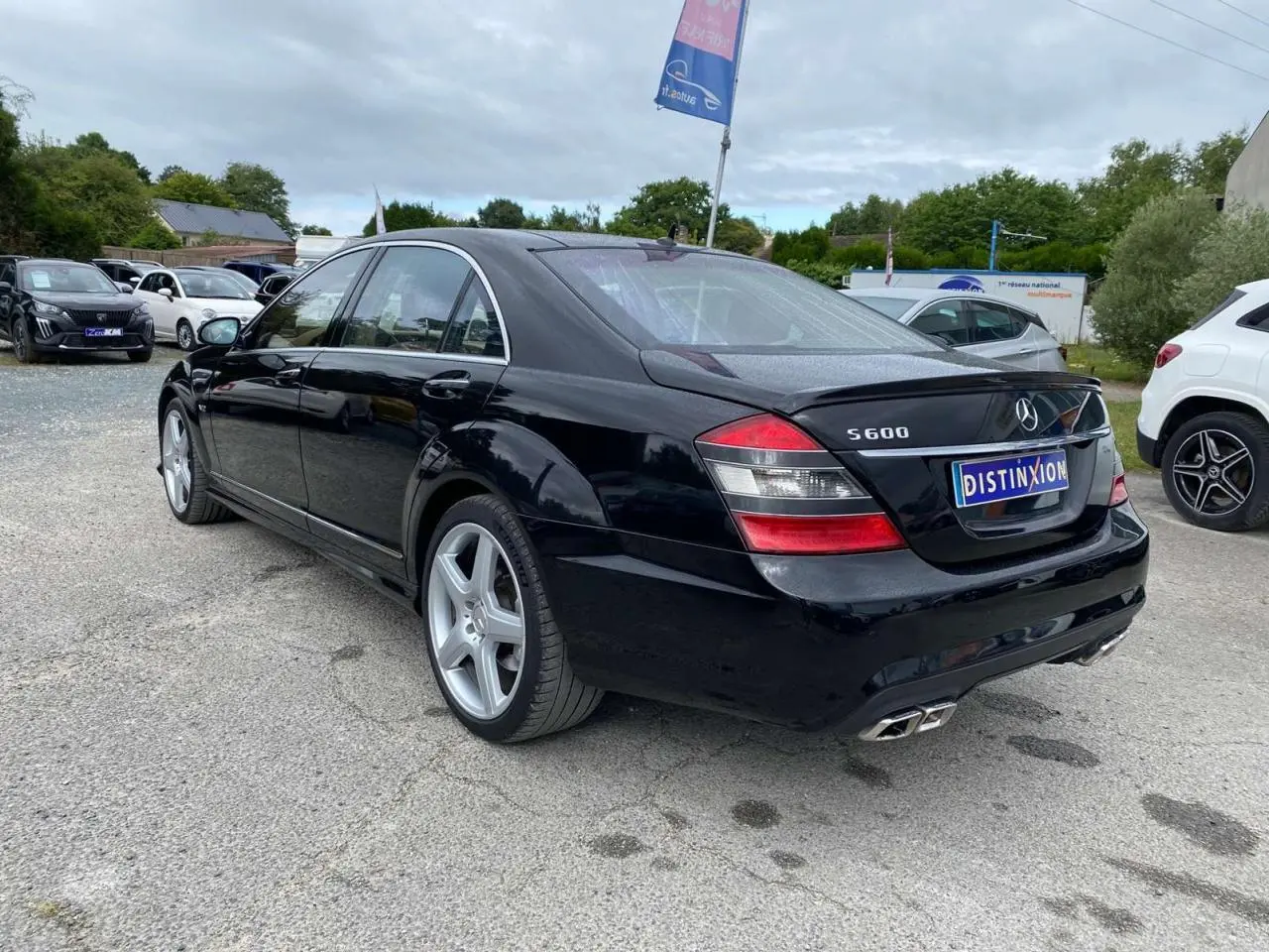 Vue 3/4 arrière droite d'une Mercedes Classe S 600 L noire avec jantes AMG 20 pouces et double sortie d'échappement AMG.