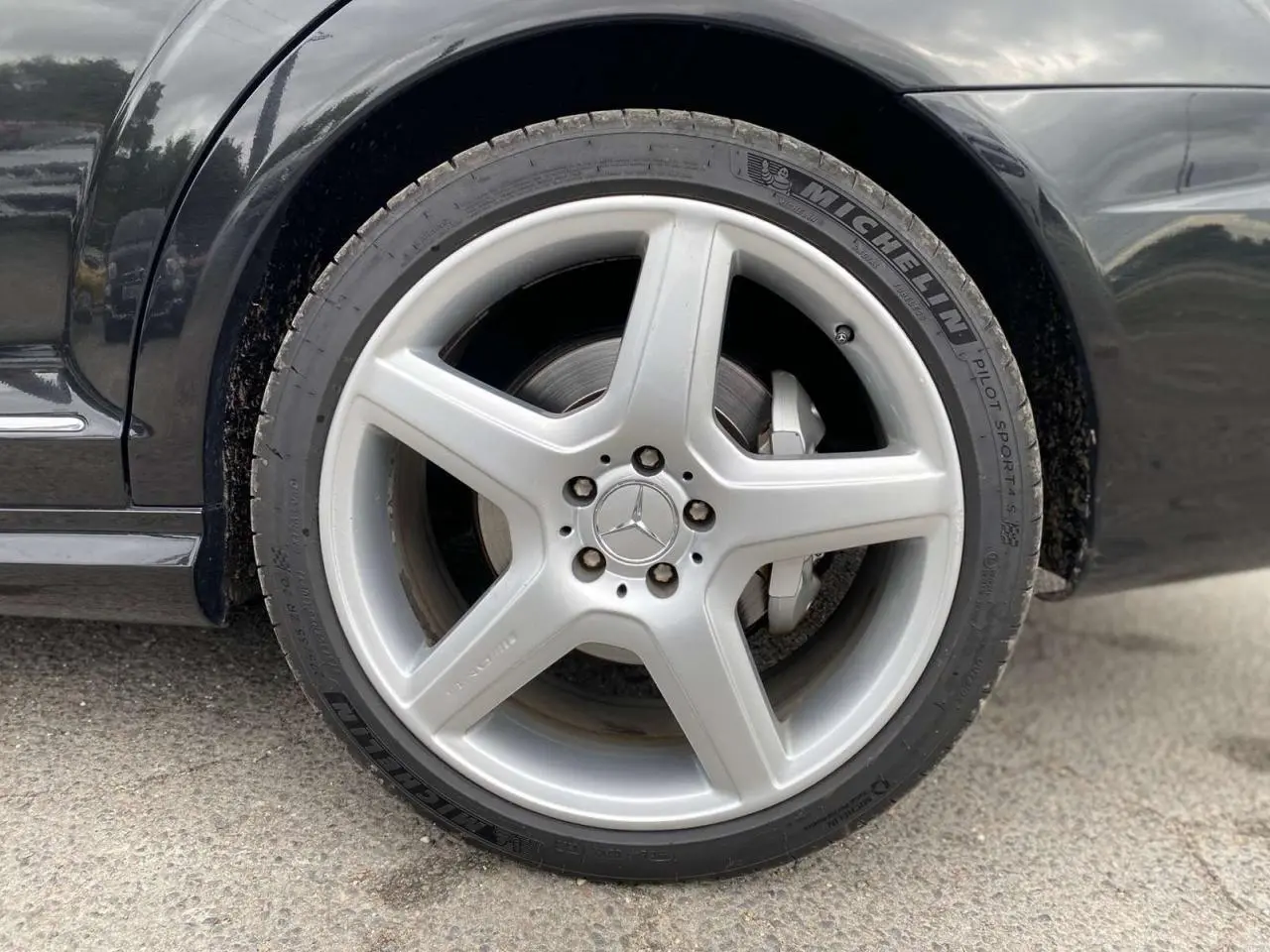 Gros plan sur la jante alliage AMG 5 branches argentée de la roue avant gauche d'une Mercedes Classe S noire.