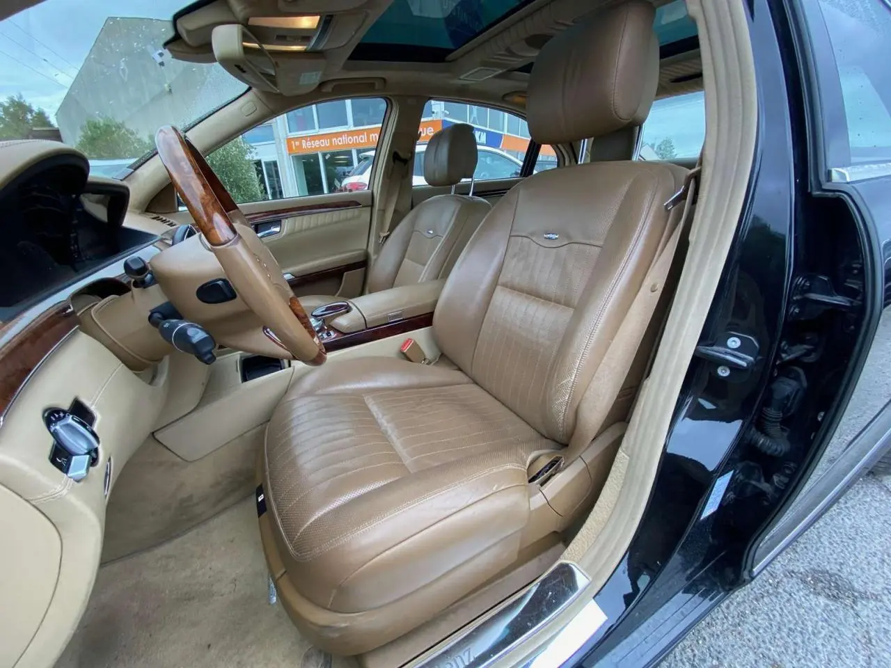Intérieur de la Mercedes Classe S 600 L 2007, vue côté conducteur, sellerie cuir beige et bois Designo noir extérieur.