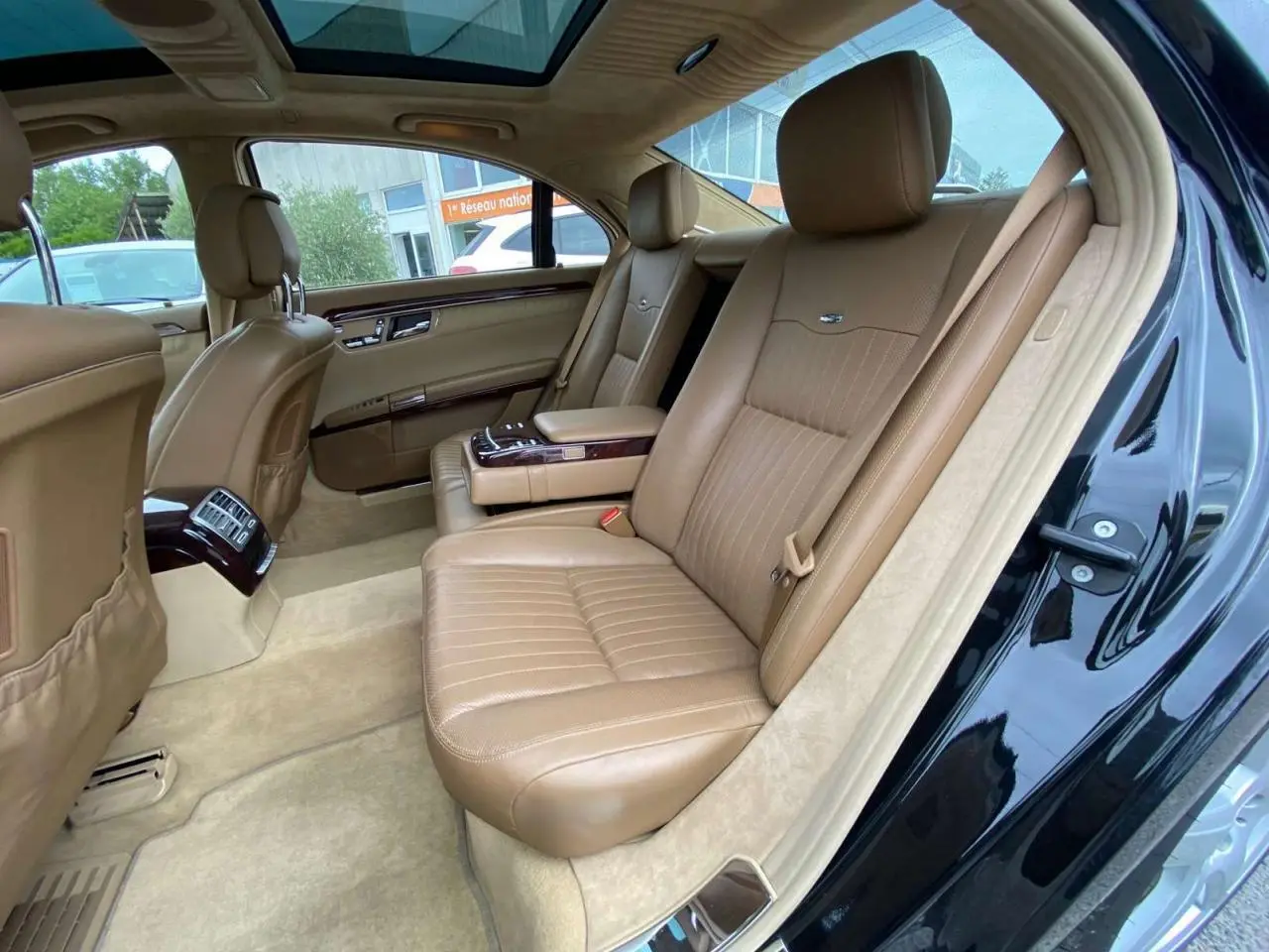 Vue côté droit de l'intérieur arrière d'une Mercedes Classe S 600 L noire avec sellerie cuir Designo beige et toit ouvrant panoramique.