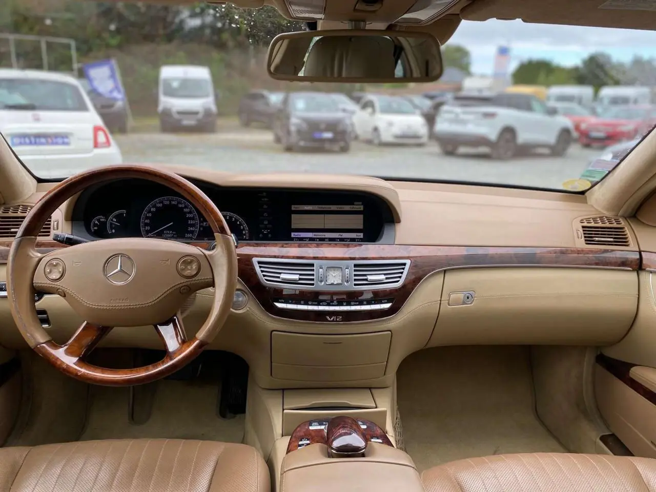 Intérieur beige clair d'une Mercedes Classe S 600 L 2007, vue frontale sur le tableau de bord en bois Designo et volant cuir-bois.