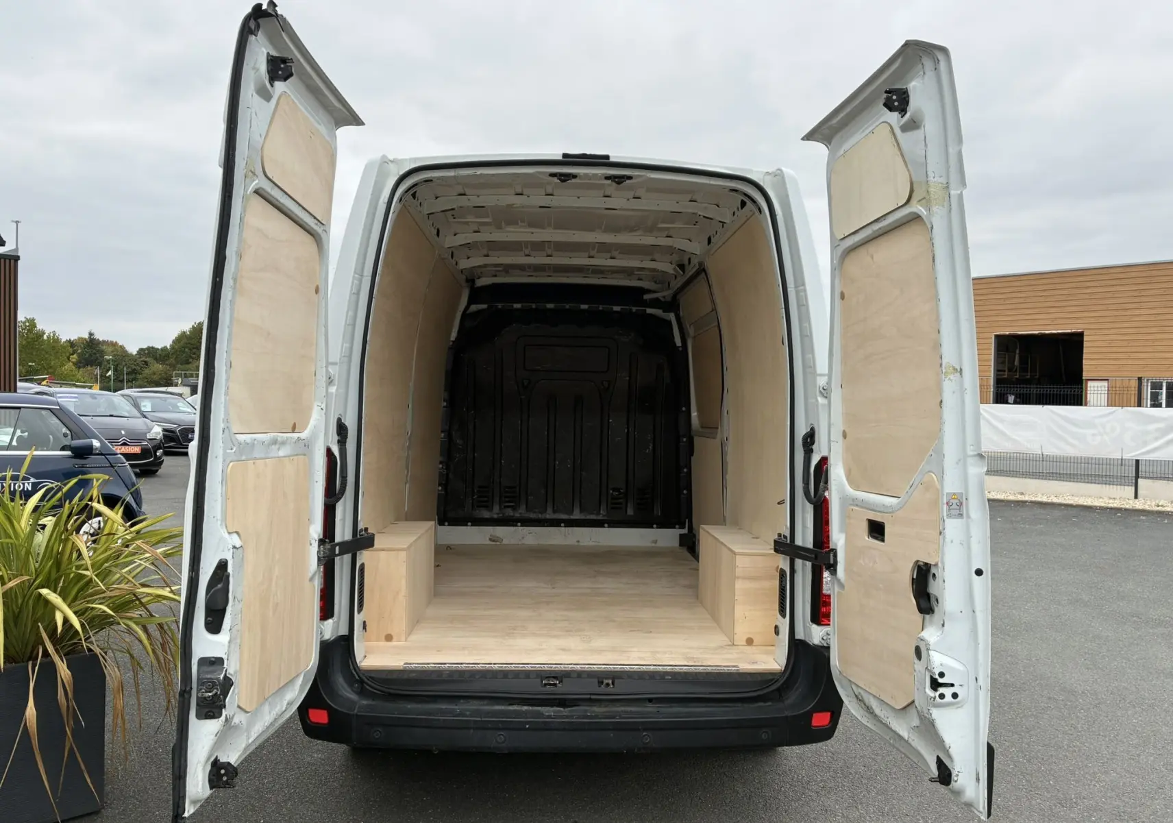 Vue arrière ouverte d'un Opel Movano Fourgon blanc 2017 avec intérieur de chargement en bois clair.