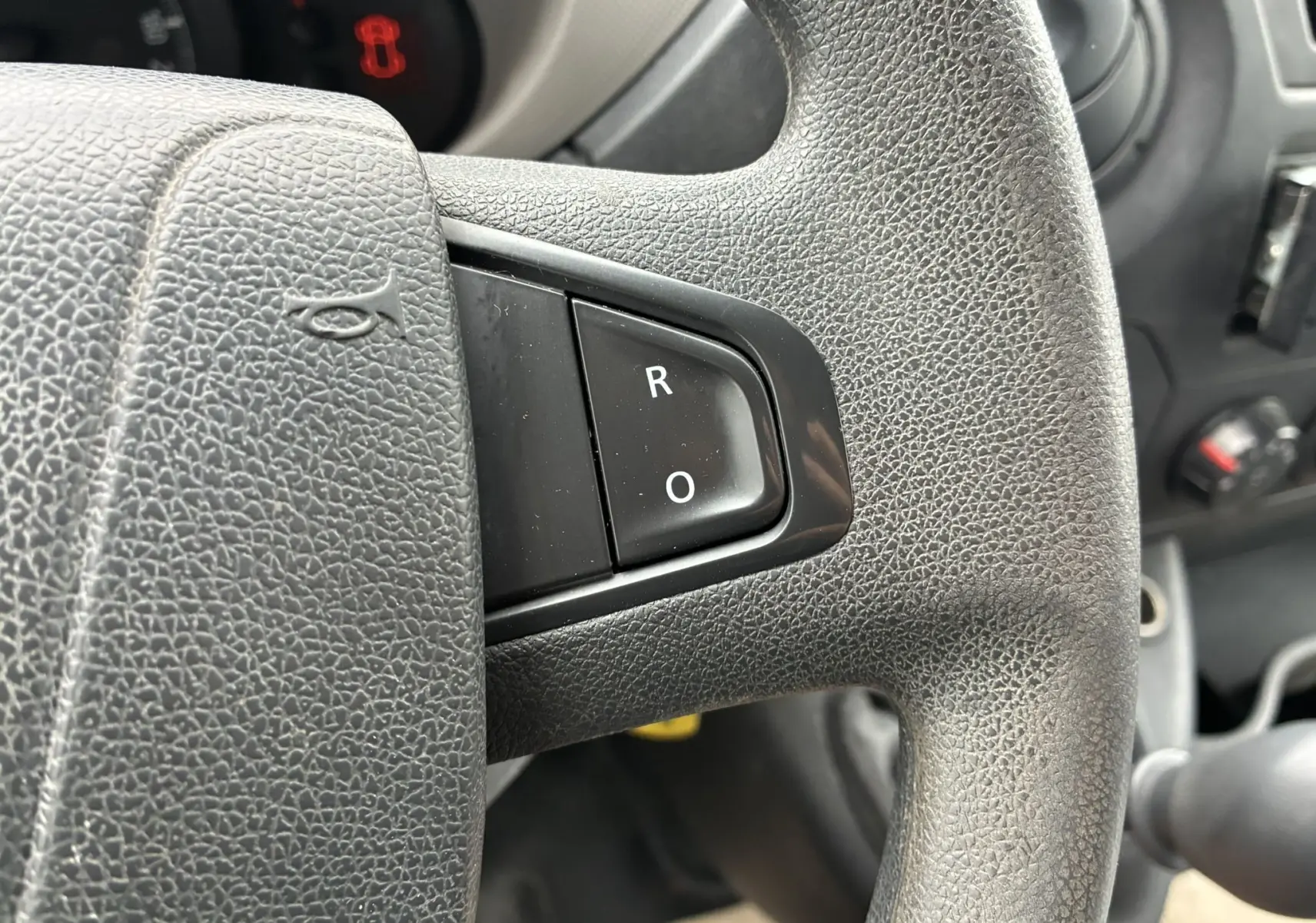 Gros plan sur le volant noir texturé de l'Opel Movano Fourgon 2017 avec boutons R et O visibles.