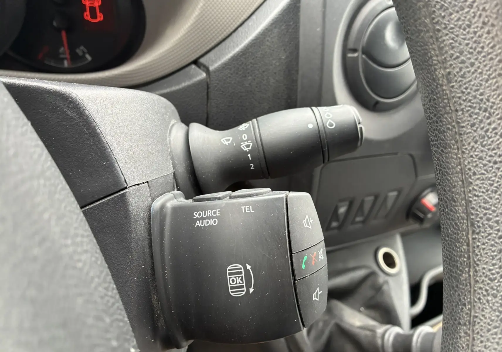 Gros plan sur la commande audio et téléphone noire à gauche du volant dans l'habitacle du fourgon Opel Movano blanc.