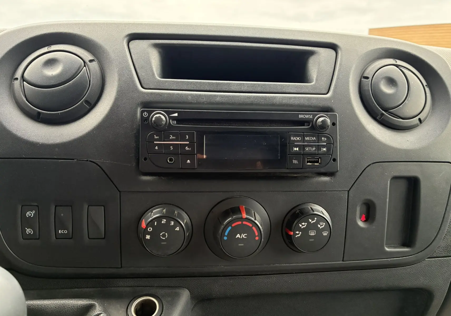 Tableau de bord noir de l'Opel Movano Fourgon blanc 2017, avec commandes climatisation et radio intégrée.