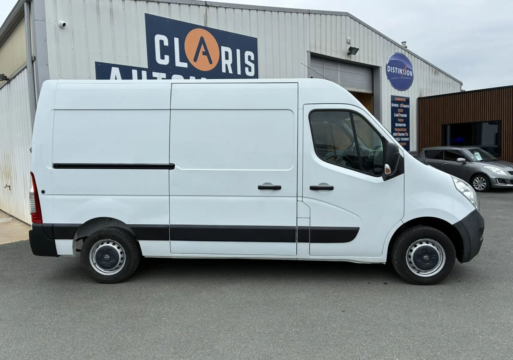 Profil droit d'un fourgon Opel Movano blanc 2017, version L2H2, avec bandeaux noirs et jantes acier simples.