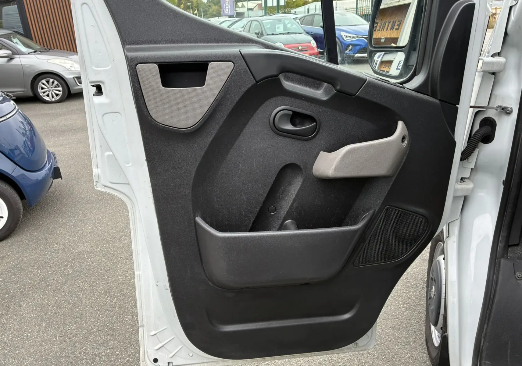 Vue rapprochée de la porte côté gauche ouverte d'un Opel Movano Fourgon blanc, avec panneau intérieur noir et poignée grise.
