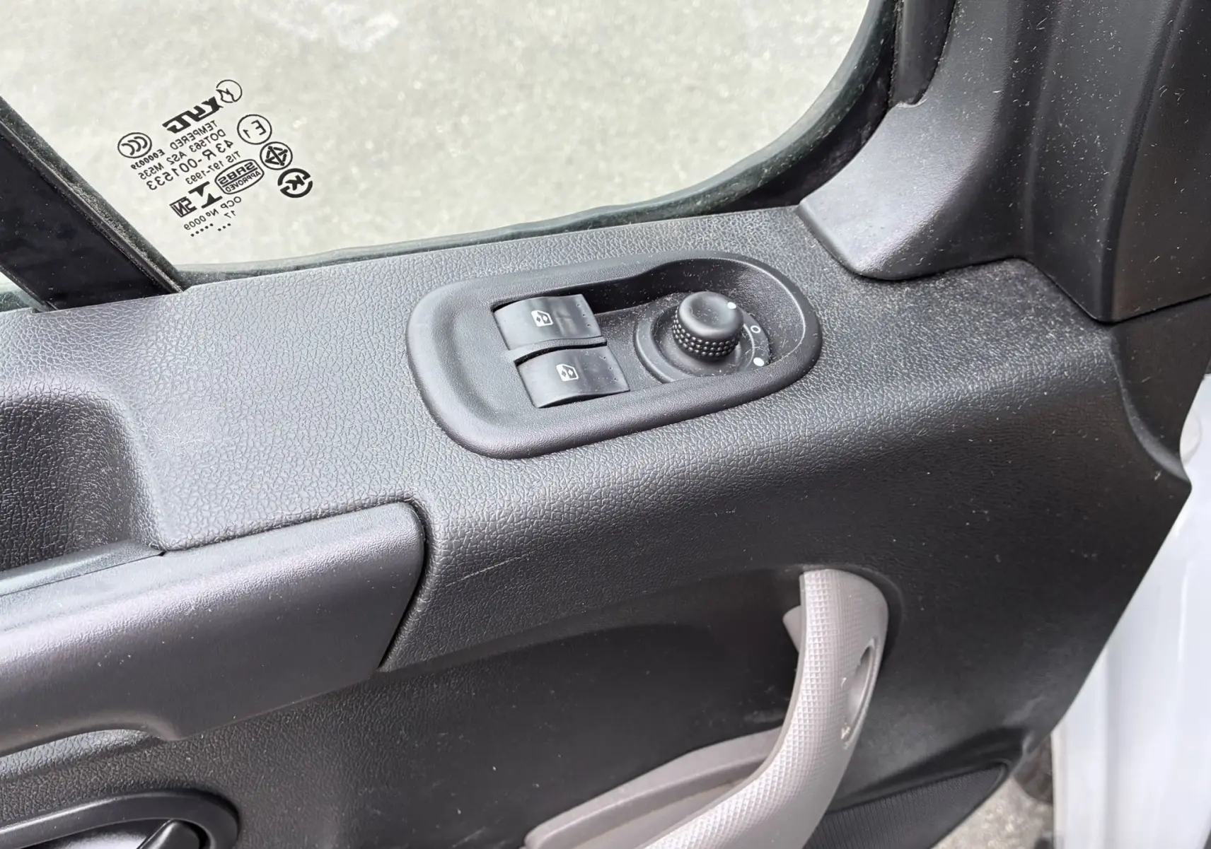 Gros plan sur la commande des vitres et réglage des rétroviseurs côté conducteur d'un Opel Movano blanc 2017.